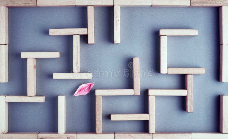 Aper boat trying to fing its way towards the exit in a maze or labyrinth made with wooden blocks. Struggle, challenge, solution or. Paper boat trying to fing its royalty free stock photo