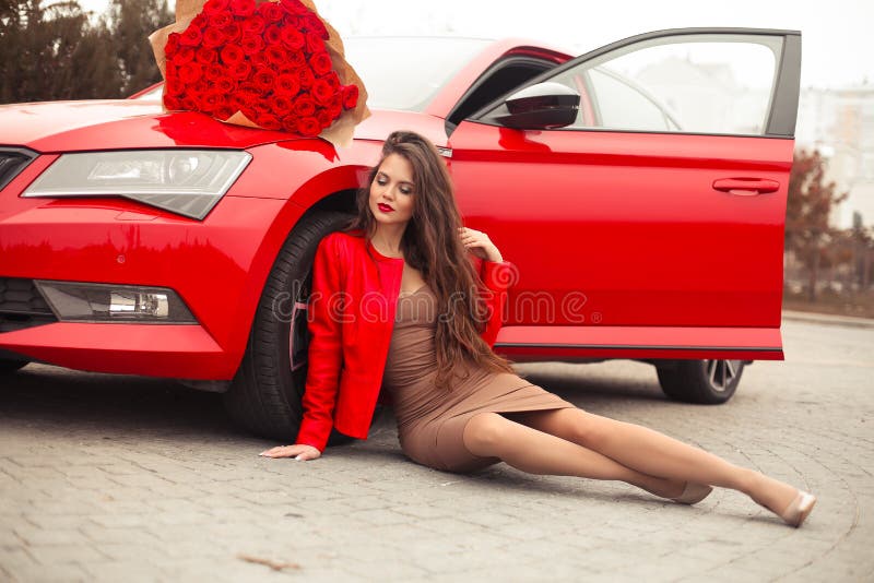 Beautiful sexy woman sitting by red car with rose bouquet of flowers. Luxury life. Beauty outdoor autumn girl portrait. Valentines. Day. Romantic expensive gift royalty free stock images
