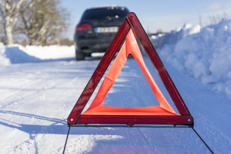 Broken car on winter road with warning sign. Image of Broken car on winter road with warning sign stock images