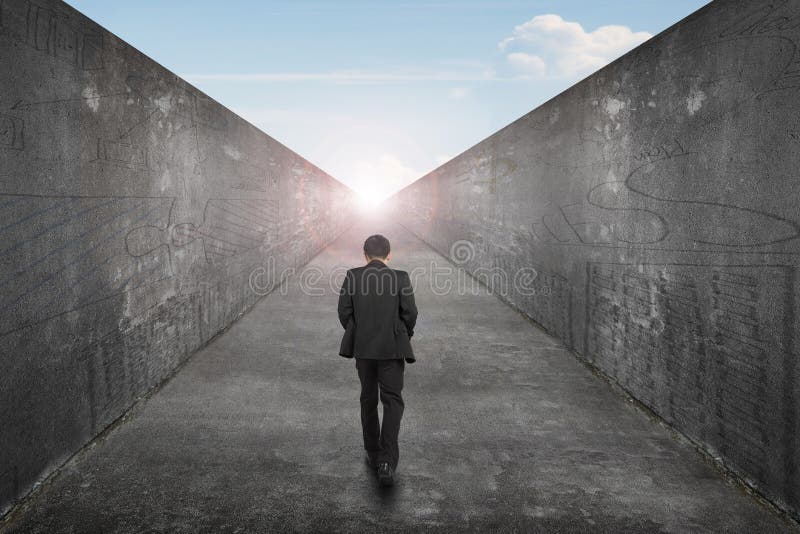 Businessman walking one way road toward exit sun sky view. Businessman walking on one way road toward the exit of sun sky view, with high dirty concrete wall royalty free stock photography