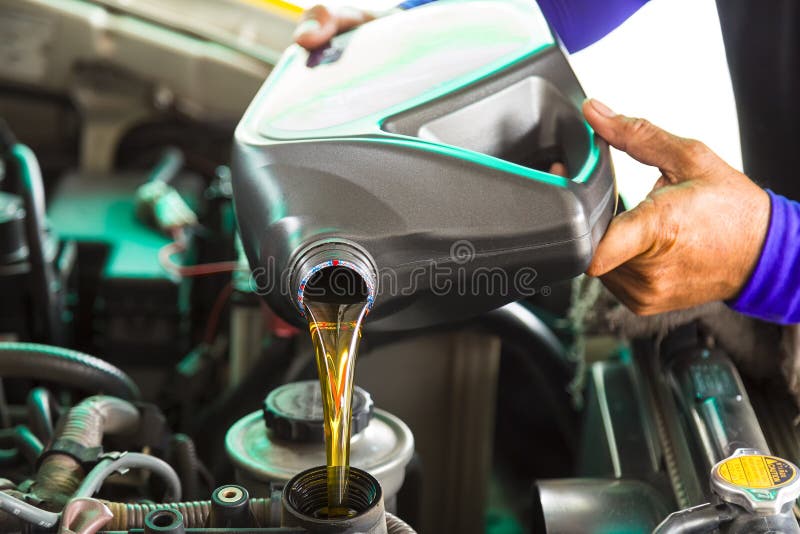 Car mechanic replacing and pouring fresh oil into engine at main stock photos