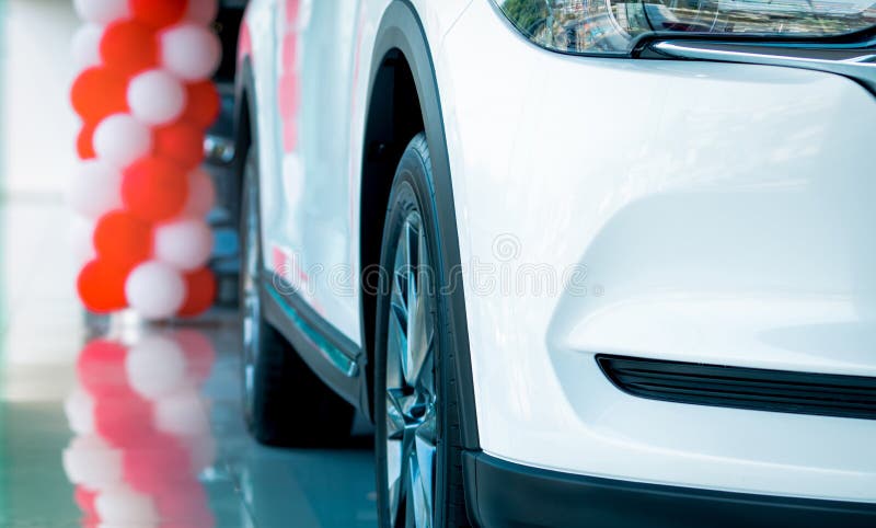 Closeup grille and wheel of new white luxury SUV car parked in modern showroom. Car dealership showroom office. Automobile leasing. Concept. Automotive industry stock photos