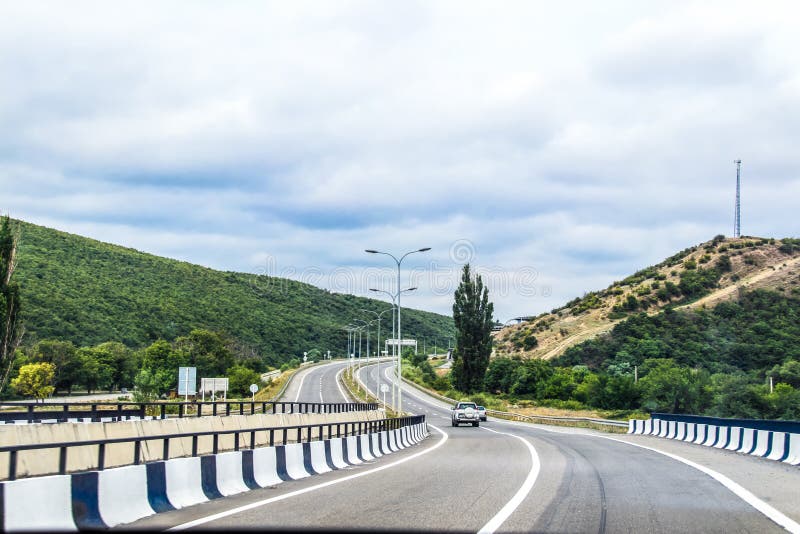 Driving north out of Tbilisi Georgia on a summer day with car and SUV going around curve ahead.  stock images