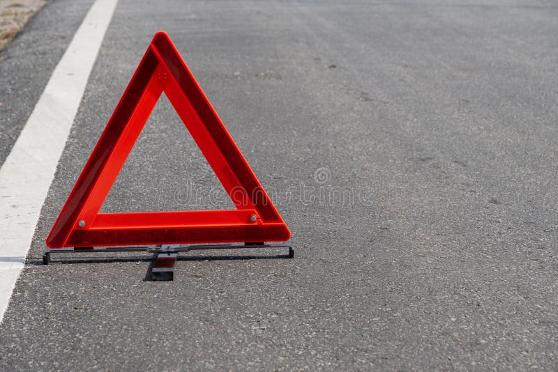 Emergency red warning triangle on the road sign with the white road line and broken car. For any design concept royalty free stock image