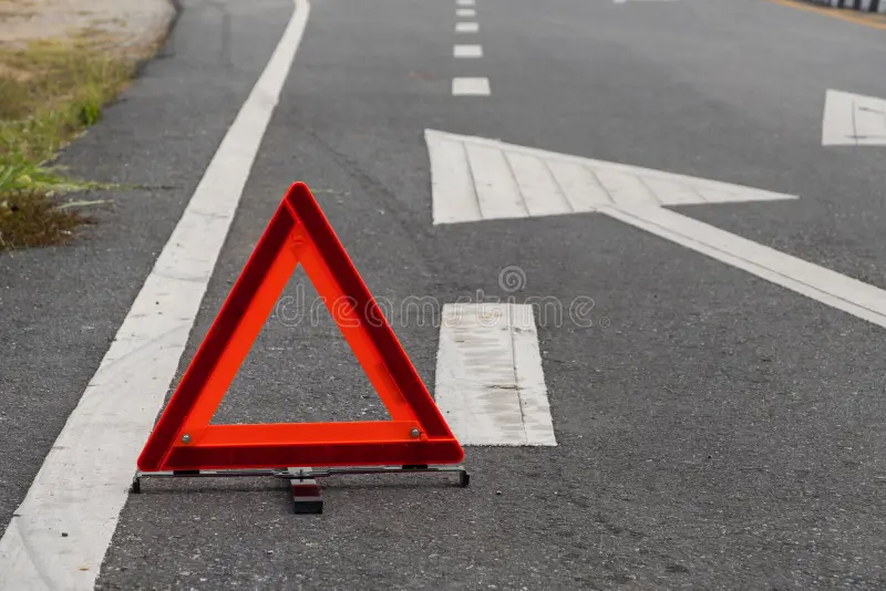 Emergency red warning triangle on the road sign with the white road line and broken car. For any design concept stock photography