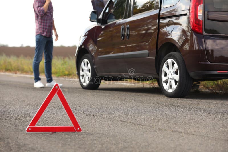 Emergency stop sign and driver near broken car on road. Auto insurance stock photo