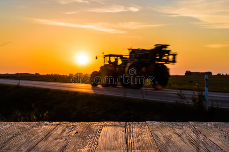 Empty rustic wood table top with tractor silhuette at sunset bac stock image
