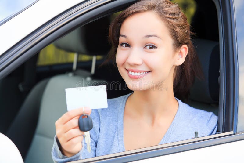 Girl in a car. Happy girl in a car showing a key and an empty white card for your message royalty free stock image