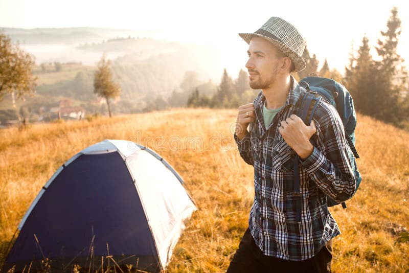 Handsome bearded man tourist exploring new places on top of mountains. Hiker man in hat with backpack happy to see sunrise. Handsome bearded man tourist royalty free stock photo