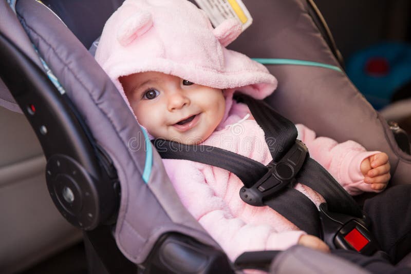 Happy baby girl in a car seat. Portrait of a beautiful baby girl sitting on a car seat and smiling stock image