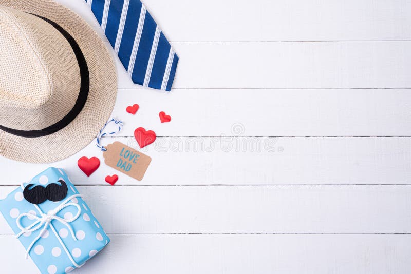 Happy fathers day concept. Top view of blue tie, beautiful gift box, man hat with glasses and retro film camera on white wooden. Table background. Flat lay royalty free stock images