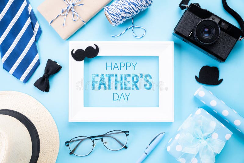 Happy fathers day concept. Top view of blue tie, beautiful gift box, man hat, white picture frame with Happy father`s day text an. D retro film camera on bright stock photo
