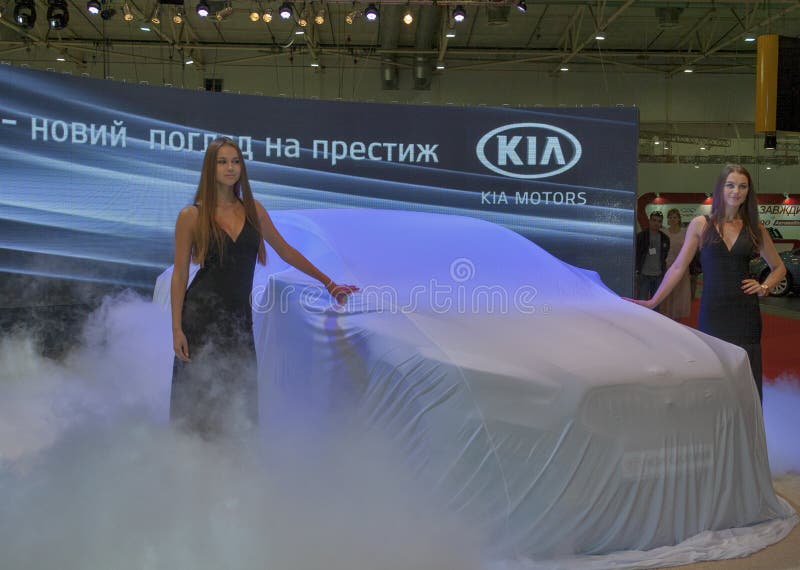 KIA Quoris car model presentation. Presenters remove the sheet from new Korean car model KIA Quoris on display of SIA 2013 Kyiv International Motor Show in stock photos