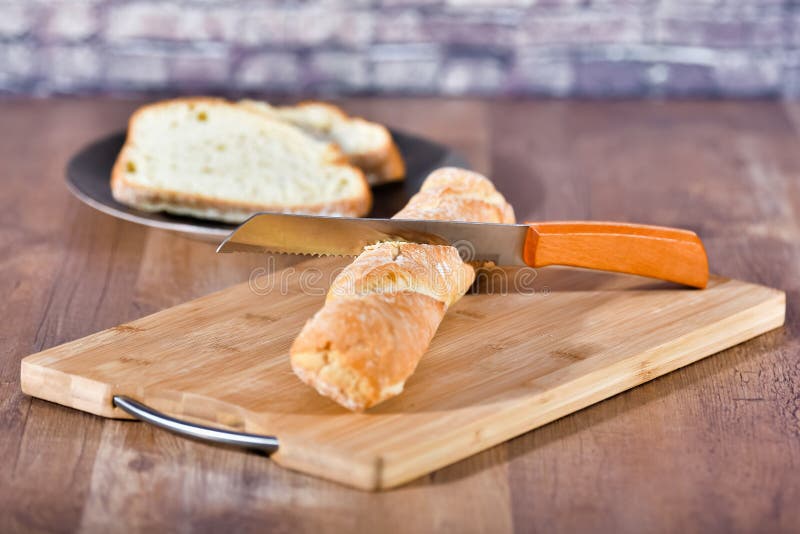 Loaf of bread on a wooden tray with a knife stuck on it stock images