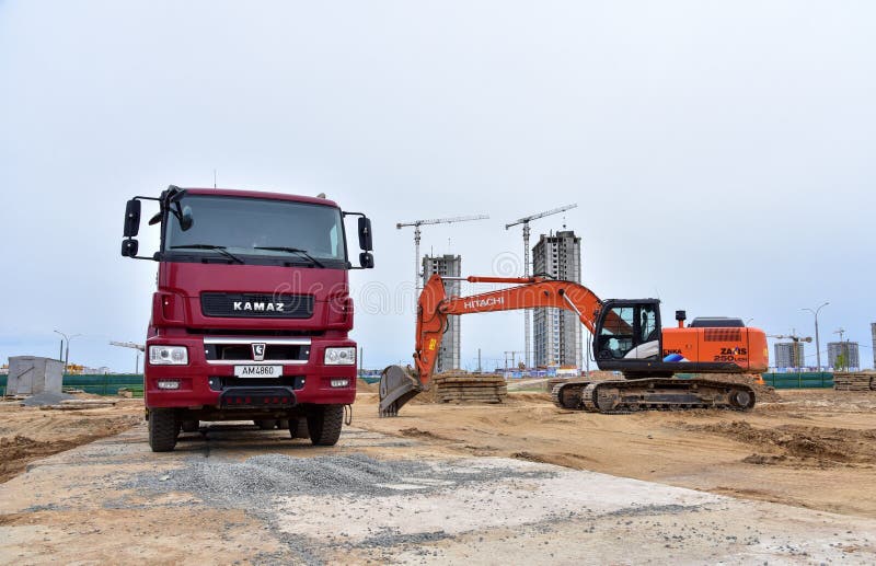 Red dump truck KAMAZ-65801-002-68Т5 8х4 and excavator HITACHI on construction site. Minsk/Belarus, MAY 25, 2020: Red dump truck KAMAZ-65801-002-68Т5 8х4 and stock photo