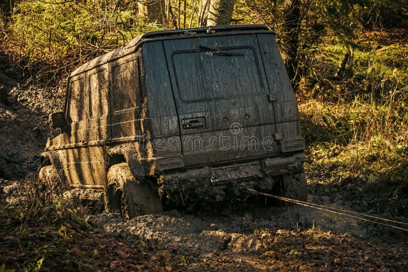 Off road car going through mud in forest. Ofroad for hard man. Off road car going through mud in forest. SUV stuck on country road with nature on background royalty free stock photography