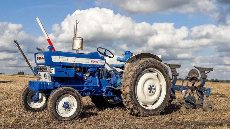 Old ford 4000 tractor ploughing. Old vintage blue ford 4000 tractor ploughing at ploughing match show. cloudy sky royalty free stock images