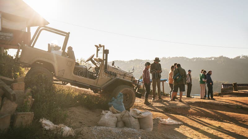 People are on the hill when the sun is going down at golden hour with SUV 4X4 car on the left in the Akha village of Maejantai. People are on the hill when the royalty free stock images