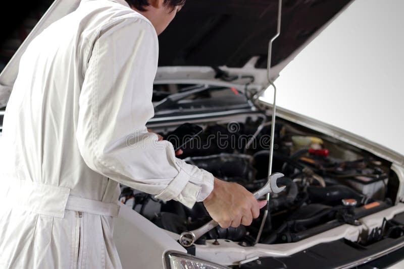 Rear view of automotive mechanic in white uniform with wrench diagnosing engine under hood at the repair garage. Car insurance co stock image