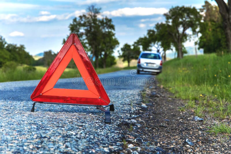 Red emergency stop sign and broken silver car on the road. Warning triangle on a country road in the Czech Republic.  stock photo