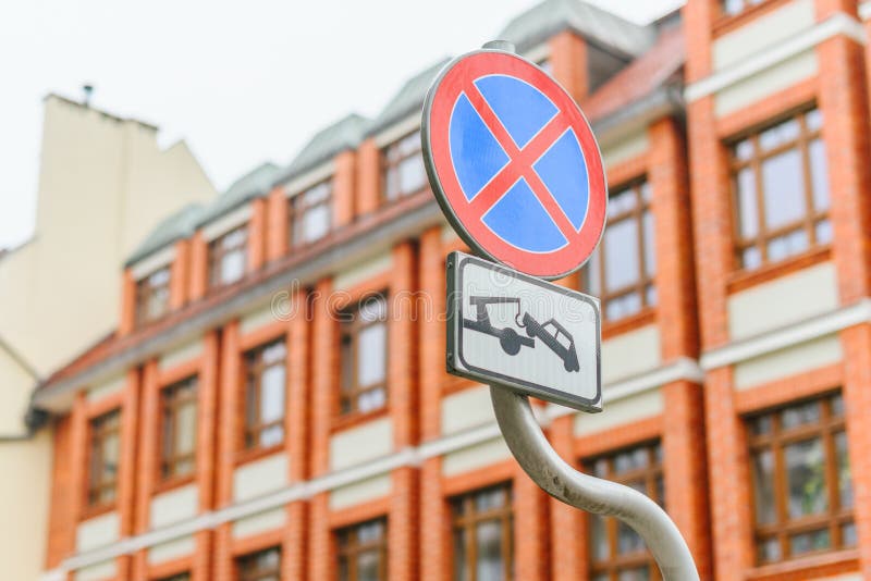 Road signs Parking is prohibited and car evacuation on a brick building with large windows background. Road signs Parking is prohibited and car evacuation on a stock photos