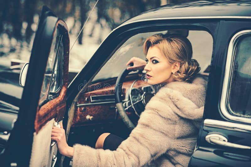 Sexy woman in fur coat. Call girl in vintage car. Travel and business trip or hitch hiking. Retro collection car and. Auto repair by driver. Escort and security royalty free stock images