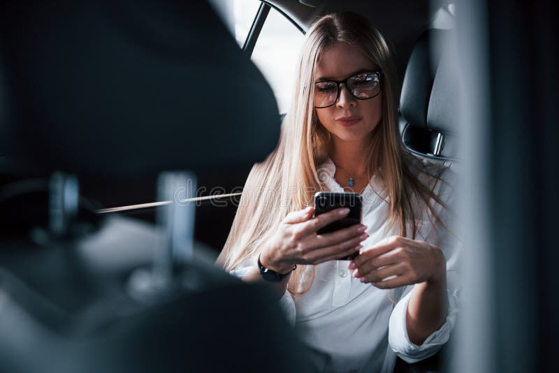 In the social medias. Smart businesswoman sits at backseat of the luxury car with black interior.  stock images