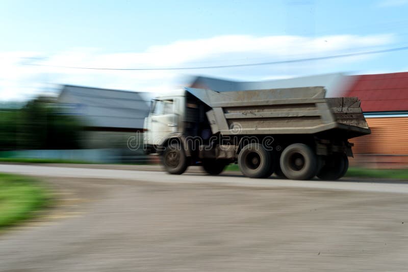 Speeding Russian Kamaz Lorry. Industrial Russian Kamaz vehicle covered in dust with motion blur moving along a dusty road stock images