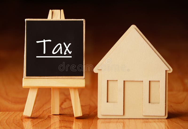 Wooden house stand with a sign tax. Selling a house or apartment and property. housing and real estate. Real estate sales stock images
